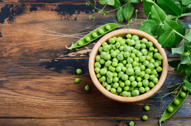istock Fresh organic green peas on rustic wooden background. 1001672102
