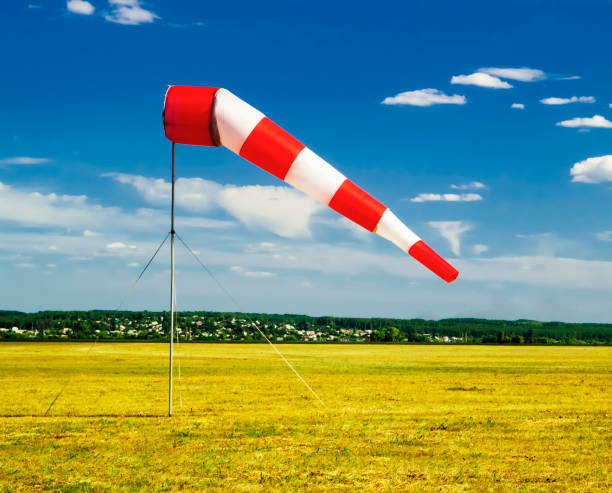 istock red and white windsock wind sock on blue sky on the aerodrome, yellow field and clouds background 1001672666