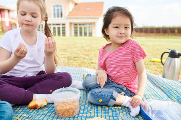 istock Girls Enjoying Picnic on Lawn 1001673496