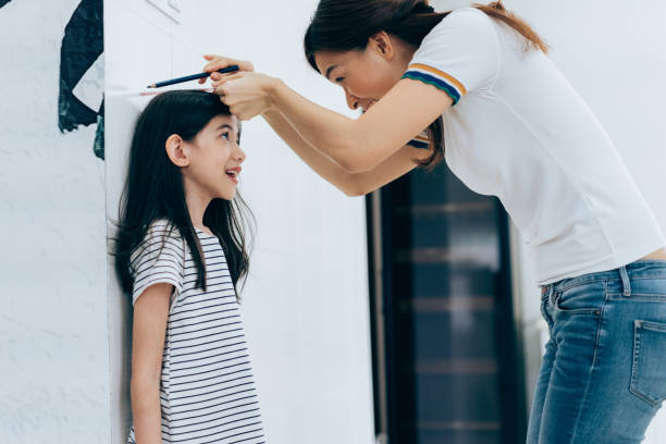 maman en mesurant la croissance de sa fille - tall human height women measuring photos et images de collection