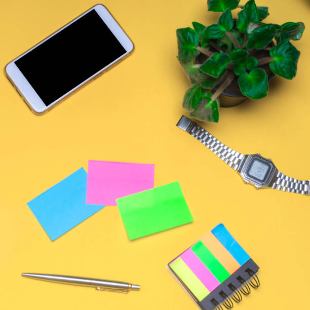 istock working space with a clock, telephone, stickers, notes on a yellow background. place for text. The working space of a freelancer, journalist, writer. On a bright yellow background. Top view. 1001680928