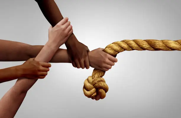 Hands pulling rope as a team effort business concept and diverse teamwork metaphor success as a group of multicultural people in a tug of war.