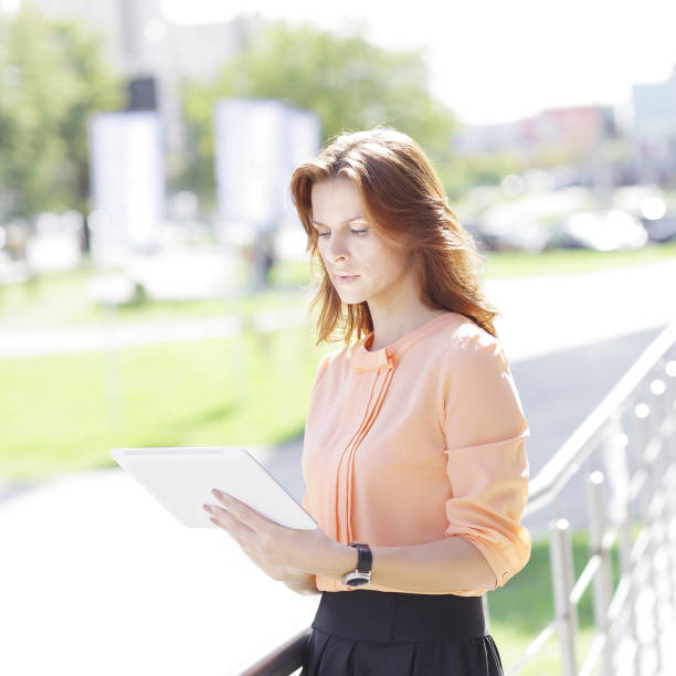 istock serious young woman with digital tablet on blurred city background 1001688218