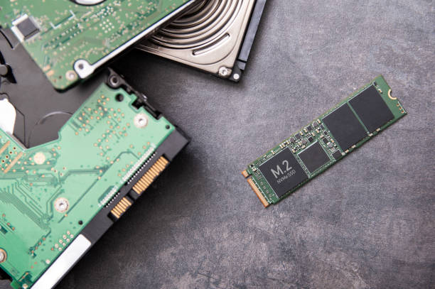 Modern M.2 SSD drive and old hard disk drives lie on a stone slab stock photo