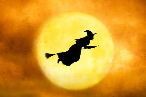 Photo of Halloween Witch Silhouetted Against Full Moon