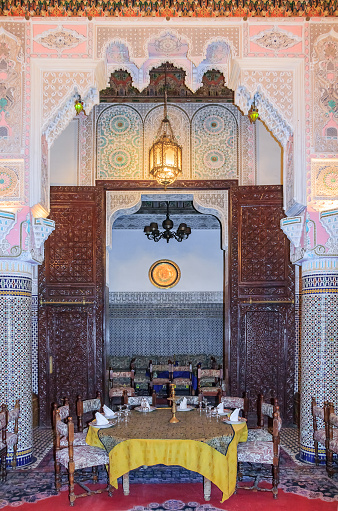 Fes, Morocco - May 11, 2013: Interior of a Moroccan restaurant with ornate mosaic and colorful arabesque plaster and cedar wood carvings in Fes, Morocco