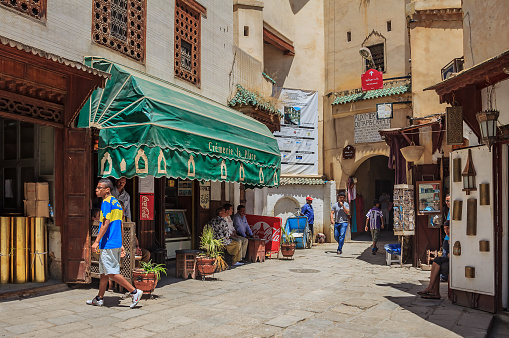Fes, Morocco - May 11, 2013: Locals and tourists walking in the medina in Fes, among souvenir shops