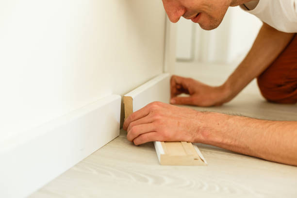 istock Man putting new skirting board in house 1001738086