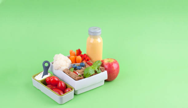 istock Office lunch in a box and juice with fruit on a green background. Free space for text. Copy space 1001738160