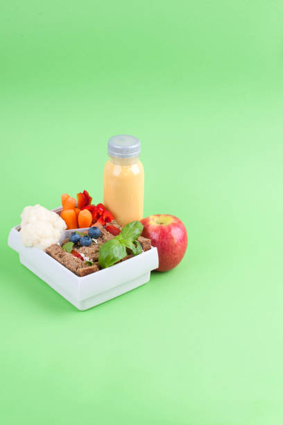 istock Lunch in a box and juice with fruit on a green background. Free space for text. Copy space 1001738348