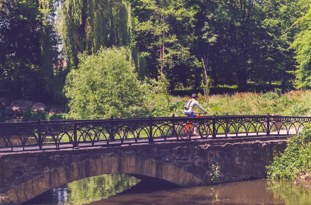 istock Cyclist in helmet riding in park on bridge 1001738432