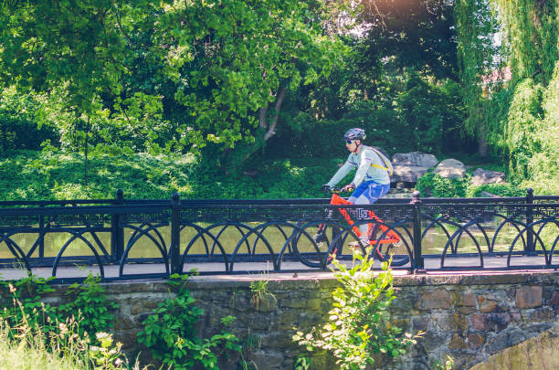 istock Cyclist in helmet riding in park on bridge 1001738480