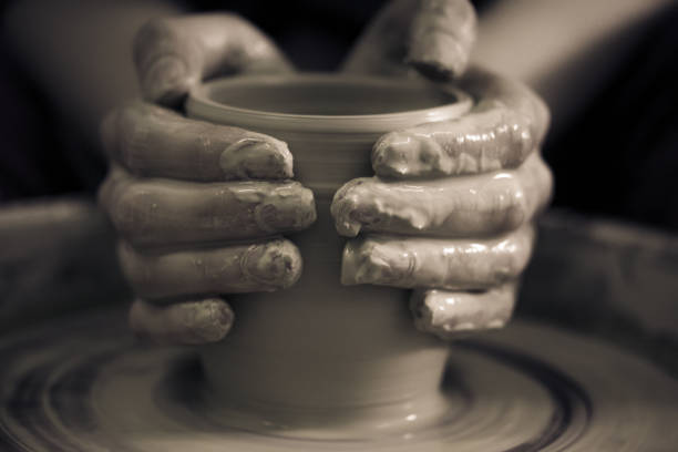 Creating ceramic products of white clay close-up Creating ceramic products of white clay close-up. The sculptor in workshop makes clay jug closeup. Master crock. Twisted potter's wheel. Art, creativity. Cultural traditions. Handmade. Craft. sculptor photos stock pictures, royalty-free photos & images