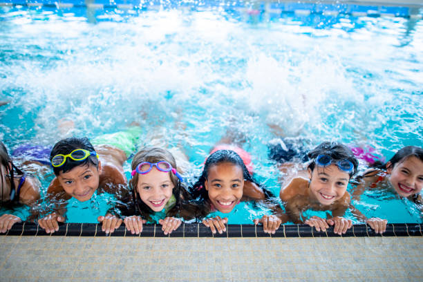 In the pool A group of elementary school children are at the pool. They are smiling and posing for the camera. swimming stock pictures, royalty-free photos & images