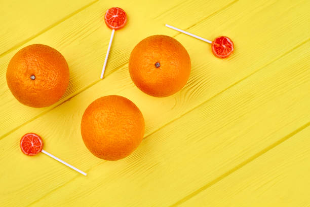 istock Fresh oranges and lollipops on wooden table. 1001780932
