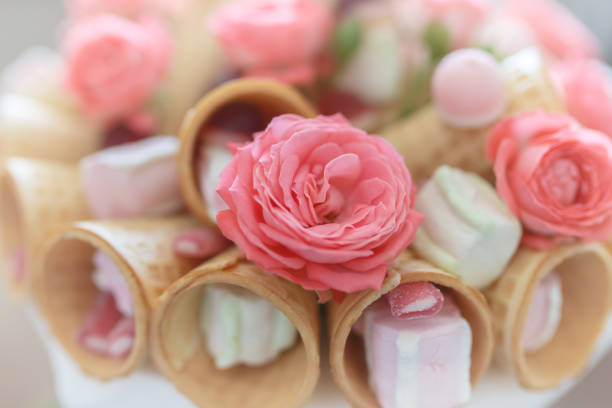 Bouquet consisting of flowers of pink roses, waffle cones, sweets and marshmallows close up