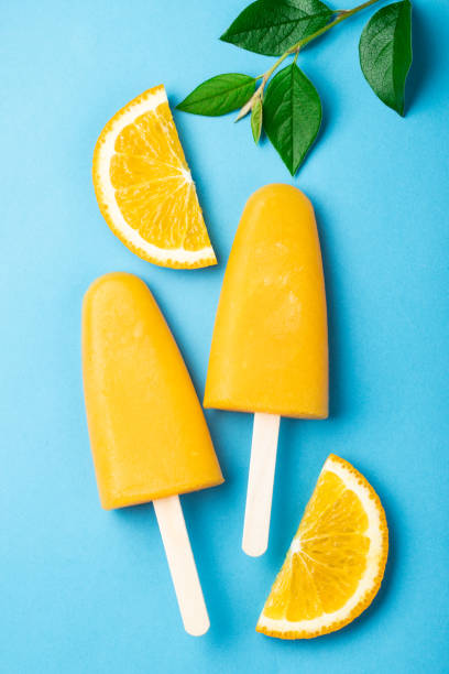 istock Orange popsicles with juice on a blue bacground. Ice pops, flat lay, top view 1001798224