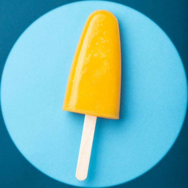 istock Single homemade orange popsicle on a blue background. Top view 1001799666
