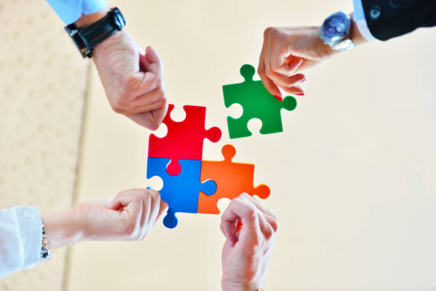 istock Group of business people assembling jigsaw puzzle and represent team support and help concept in office 1001800044
