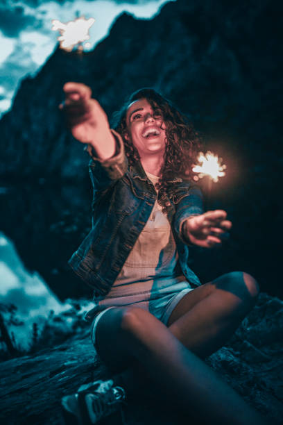 istock Cute Girl Playing With Sparklers During Camping Trip On Mountain 1001802366