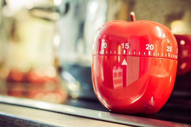 15 Minutes - Red Kitchen Egg Timer On Cooktop Next To A Pot stock photo