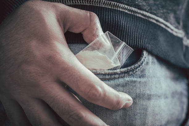 Dealer Hiding A Little Bag Of Drugs With White Powder With Hand Over His Pocket stock photo