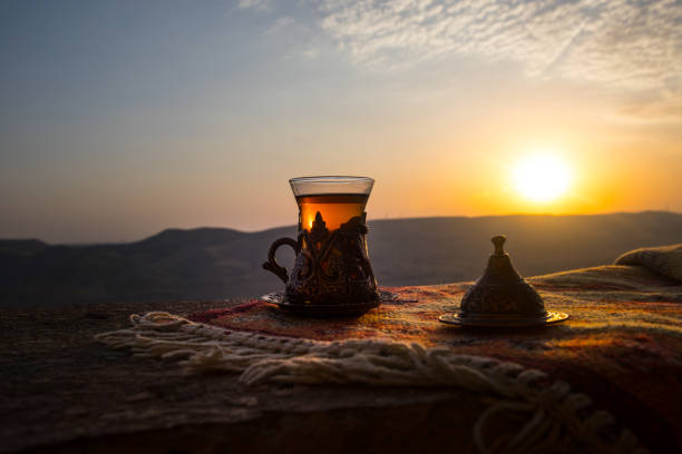 istock Arabian tea in glass on a eastern carpet. Eastern tea concept. Armudu traditional cup. Sunset background. Selective focus 1001811714