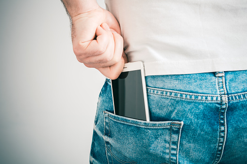 A Male Hand Grabbing A Smartphone In The Left Back Pocket Of A Jeans Trouser
