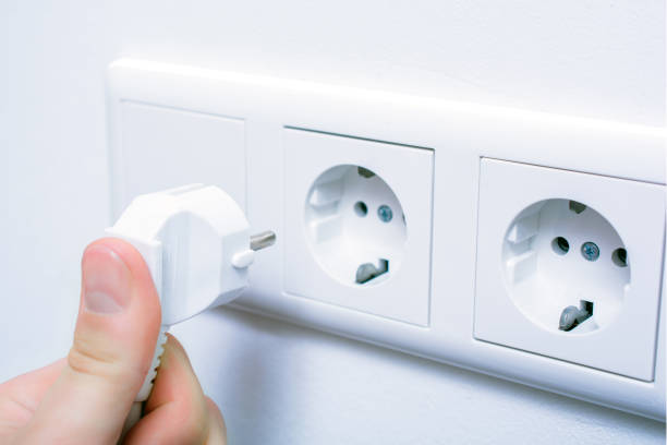 男性の手を押し、壁のコンセントにプラグを接続します。 - electric plug outlet pulling electricity ストックフォトと画像