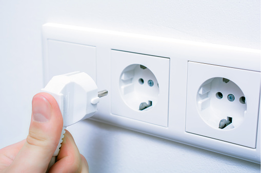 A Male Hand Is Holding And Connecting An Electrical Plug In A Wall Socket