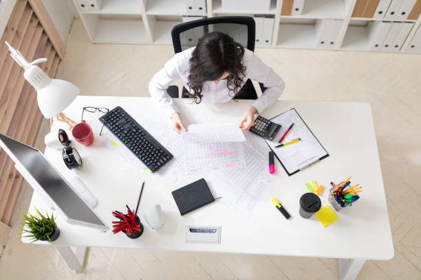 istock A young girl is sitting at the office desk and working with documents. 1001814094