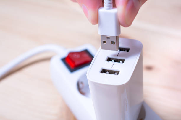 白い usb ケーブルを電源タップに接続されている白の usb 充電器に接続します。 - electric plug outlet pulling electricity ストックフォトと画像