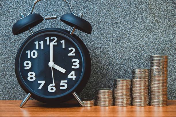 istock Alarm clock and step of coins stacks on working table, time for savings money concept. 1001814772