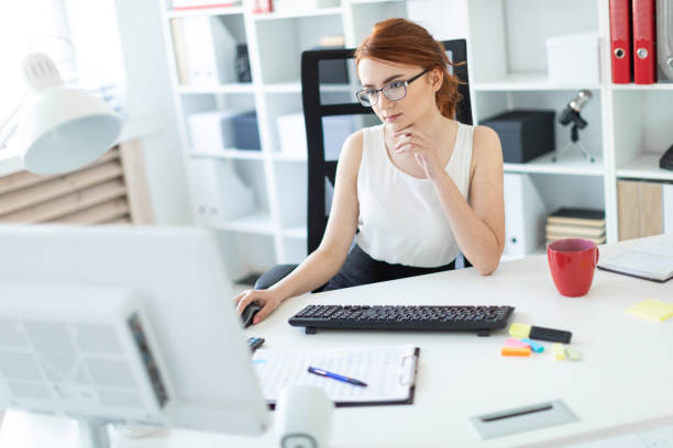 istock Beautiful young girl in the office working at the computer. 1001817336