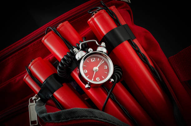 Bomb in red duffle bag in dark setting Terrorism and bomb threat concept with dynamite or TNT stick, alarm clock, black wires and a red duffle bag with dark dramatic lighting sabotage photos stock pictures, royalty-free photos & images