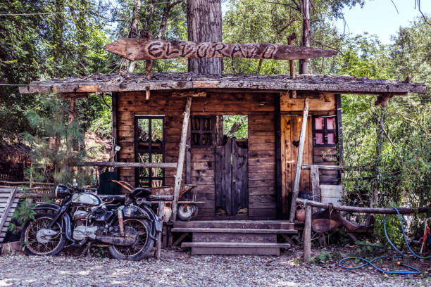 Big model of Wild West saloon and old motorcycle Nis, Serbia - July 11, 2018: Big model of Wild West saloon and old motorcycle in front of the house in nature. El dorado text on wooden plank saloon photos stock pictures, royalty-free photos & images