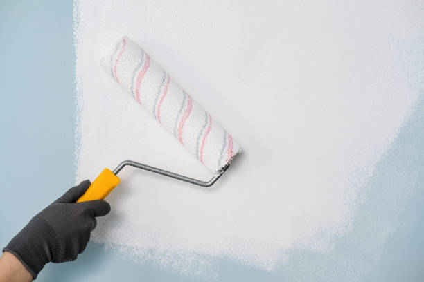 istock A hand with a roller paints the wall with white paint 1001822818
