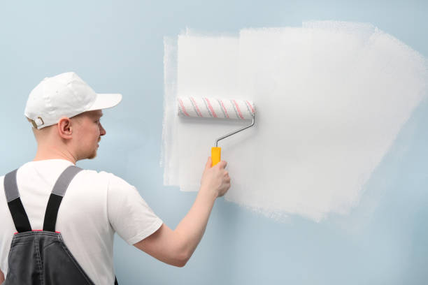 istock Man working in white T-shirt and cap is painting wall. 1001822930