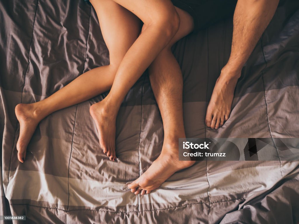 Close up of the legs of a couple on the bed. Couple - Relationship Stock Photo