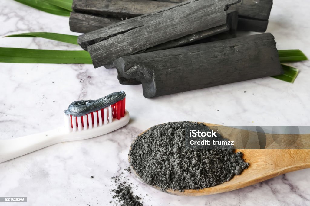 Pasta de dientes por el polvo del carbón de leña activado en mesa de mármol - Foto de stock de Carbón libre de derechos