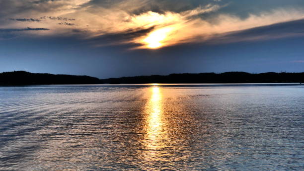 istock Sunset in a dark blue sky with bright halo on the water 1001840926