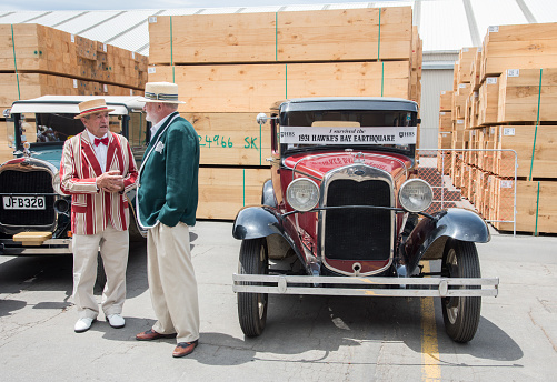 Napier, North Island, New Zealand-December 15,2016: Vintage cars with senior adults in 1930's retro fashion on dock with pallets in Napier, New Zealand