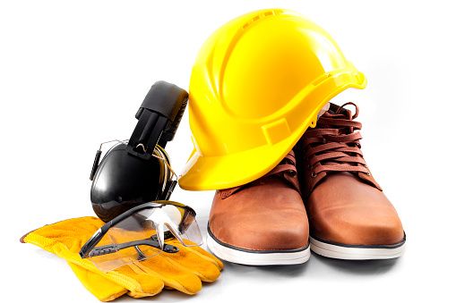 Work safety concept with hard hat, protective gloves, boots, eye safety glasses and hearing protecting noise canceling earmuffs isolated on white background with a clipping path included