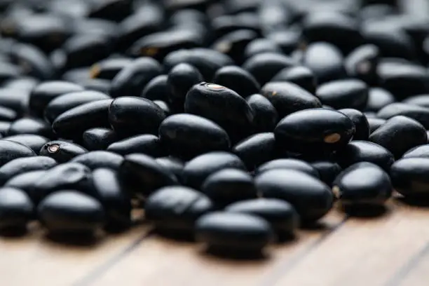 Suitable for background. A pile of raw black beans on wood.