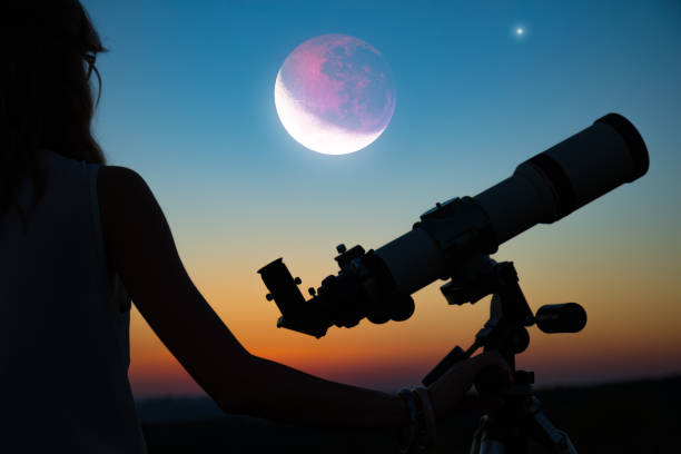 istock Girl looking at lunar eclipse through a telescope. My astronomy work. 1001890324