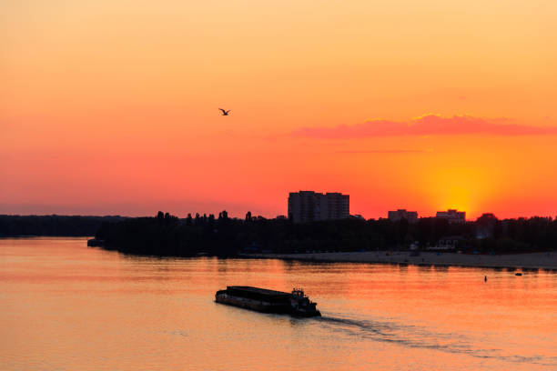 istock Tugboat pushing a heavy long barge on the river Dnieper at sunset 1001894870