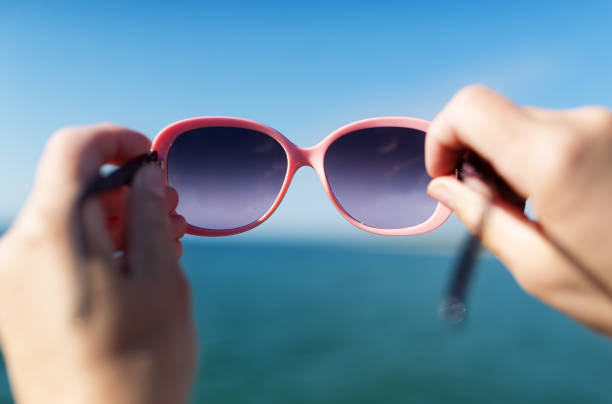 istock Soft focus on hand holding sunglasses over sea. 1001897432