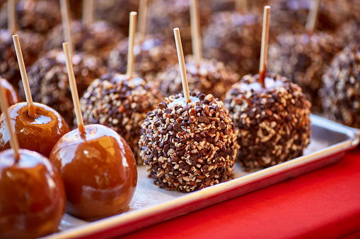 Carmel candied apples and chocolate chips and nuts coated apples on a stick