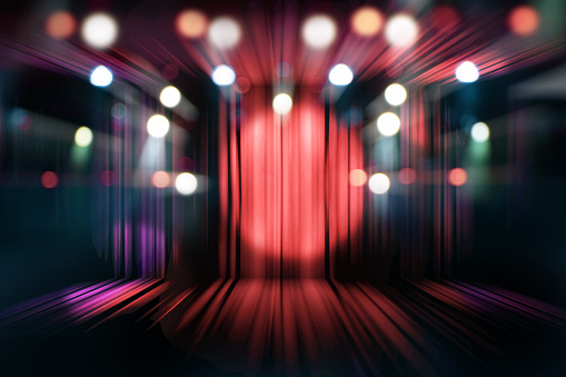 blurred theater stage with red curtains and spotlights, abstract image of concert lighting