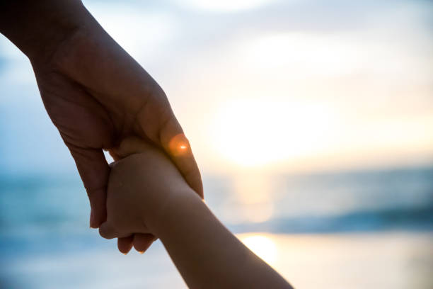 ソフト フォーカスの親は、日没、暖かい音色の中に小さな子供の手を握ってください。 - little hands ストックフォトと画像